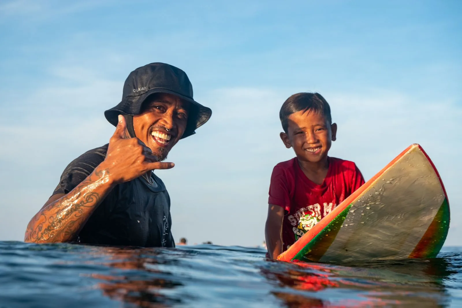Coach and young surfer sharing a shaka in the lineup at Siargao