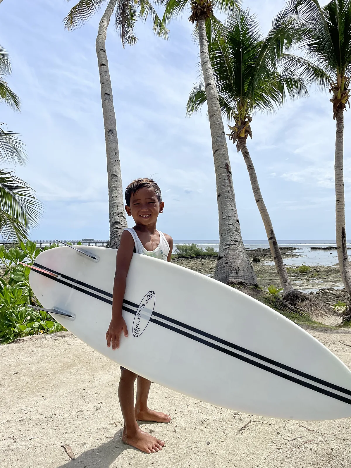 Young surfer holding a board under the palms in Siargao